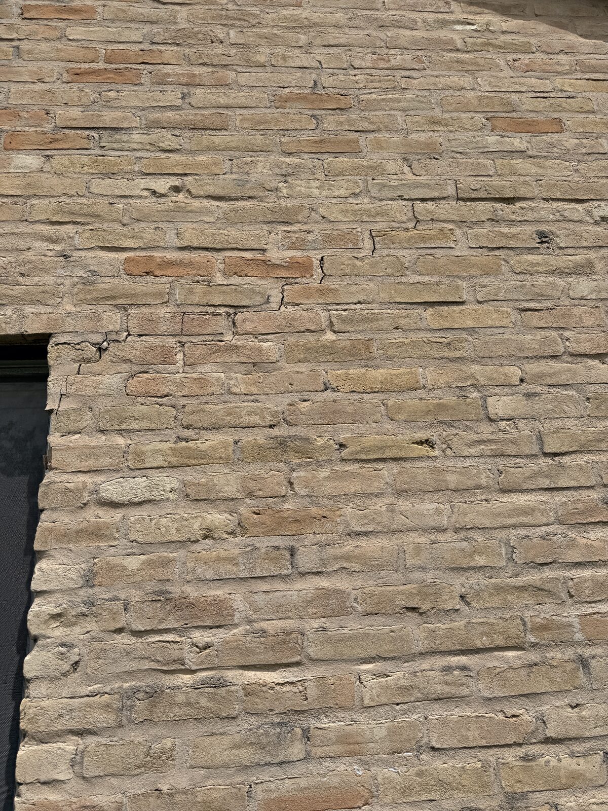 Cracked brick alongside a window jamb on a settling home, noted during a foundation evaluation