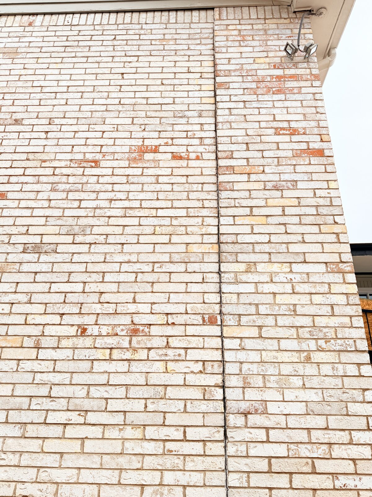 Angled view of a repointed vertical crack near a brick wall corner repaired after settlement
