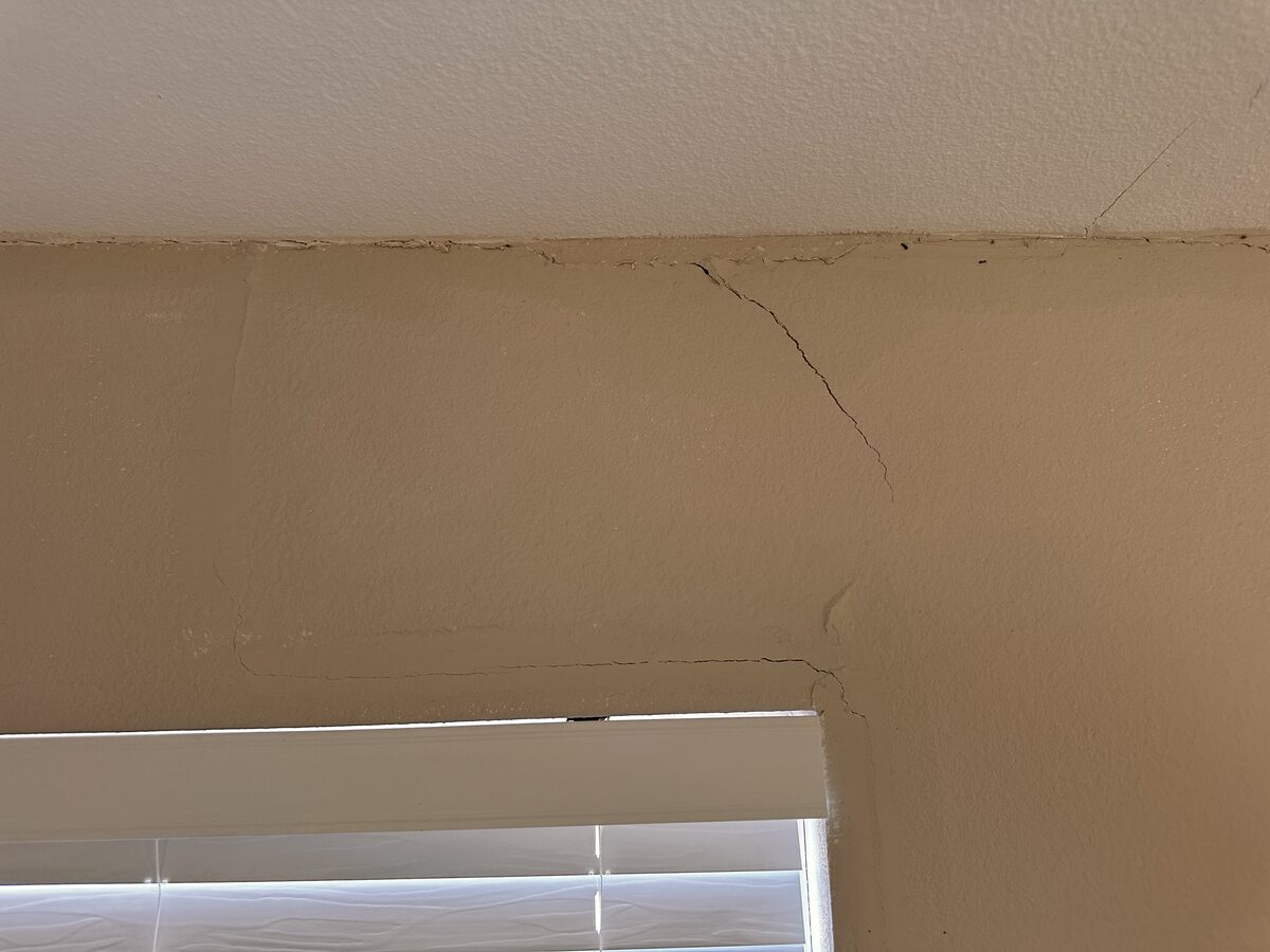 Crack at the ceiling corner above a window caused by differential foundation settlement