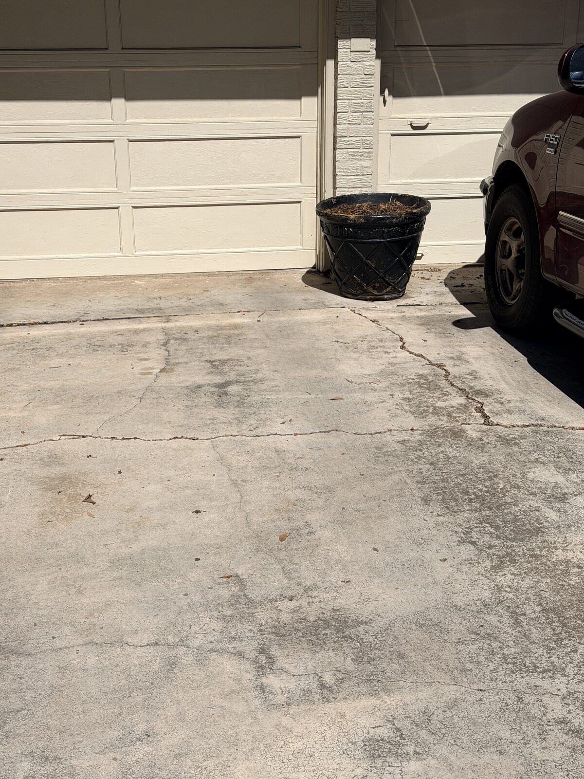 Cracked concrete driveway slab in front of a garage, often linked to soil movement under the slab