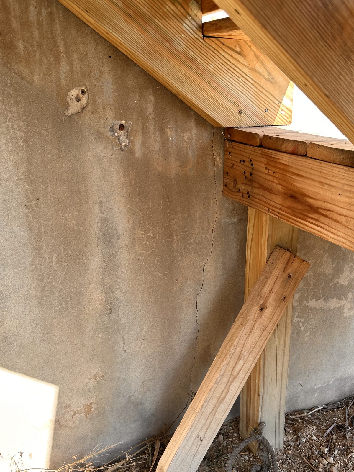 Wood deck framing built against a stucco foundation skirt wall, noted during an inspection