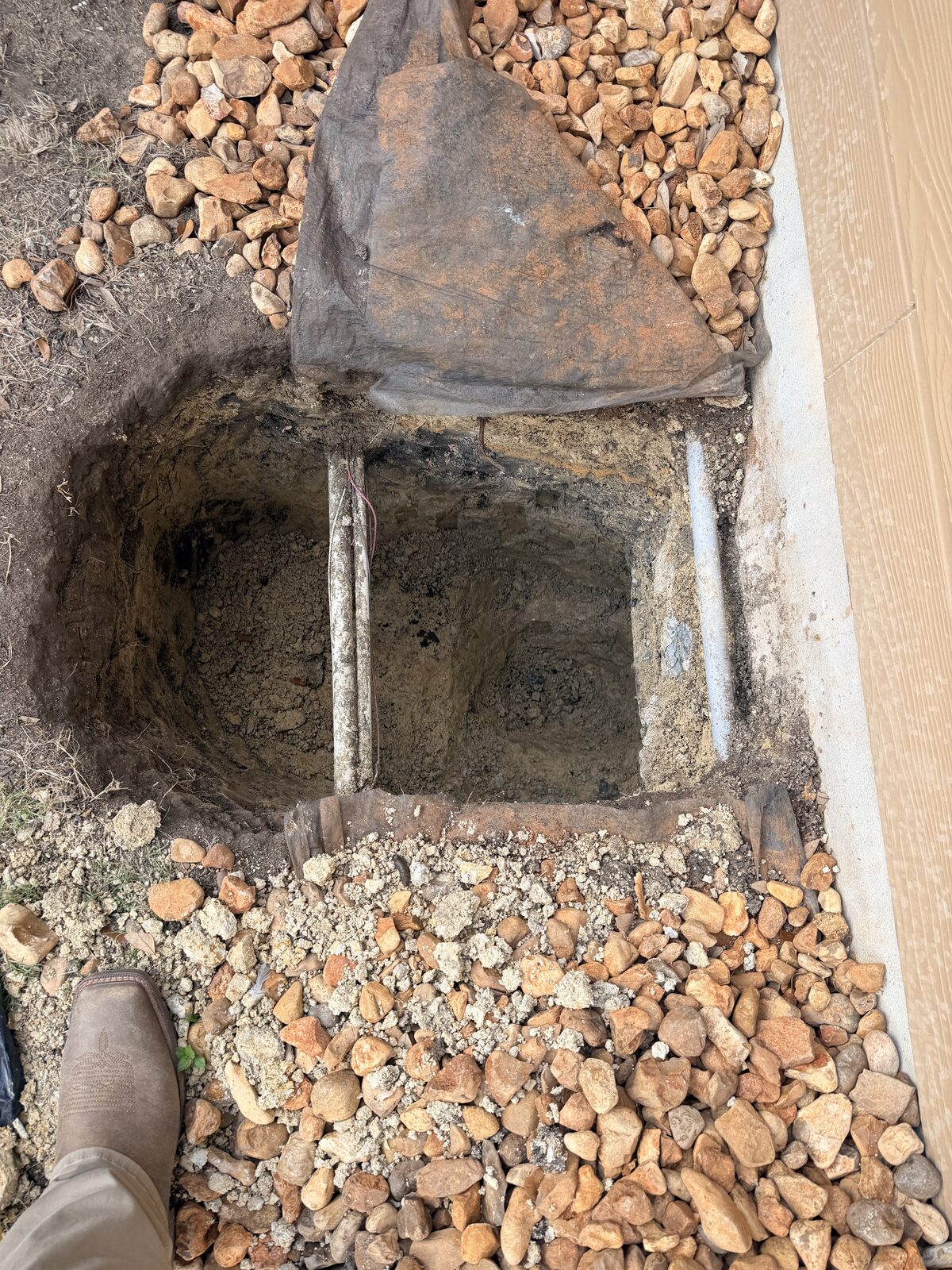 Deep pier excavation exposing the concrete grade beam beneath a slab foundation before steel piers are driven