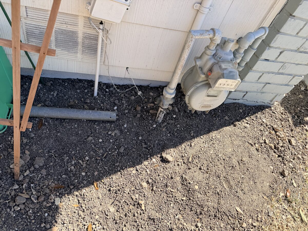 Careful foundation excavation alongside a home's gas meter and service piping during pier work