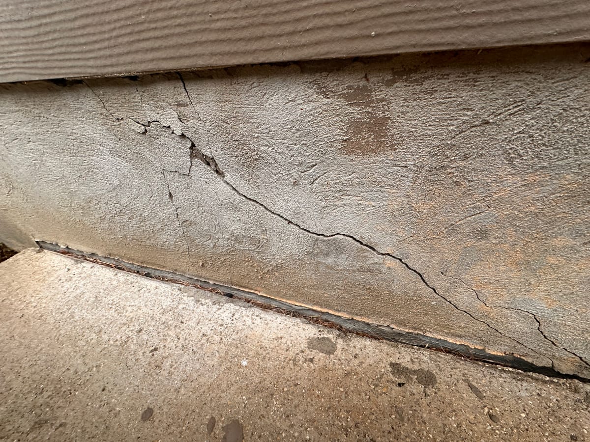 Diagonal crack and separation along a home's concrete slab edge below the siding, documented during a Motmot foundation inspection