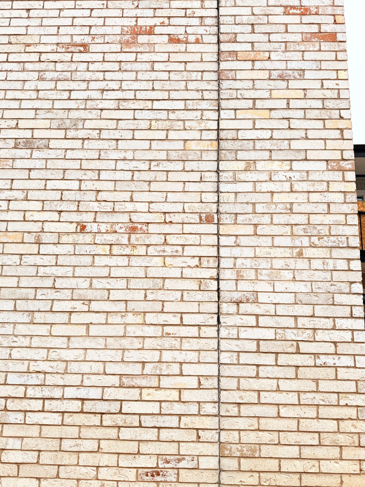 Full-height vertical crack line repointed in a painted brick wall after foundation stabilization