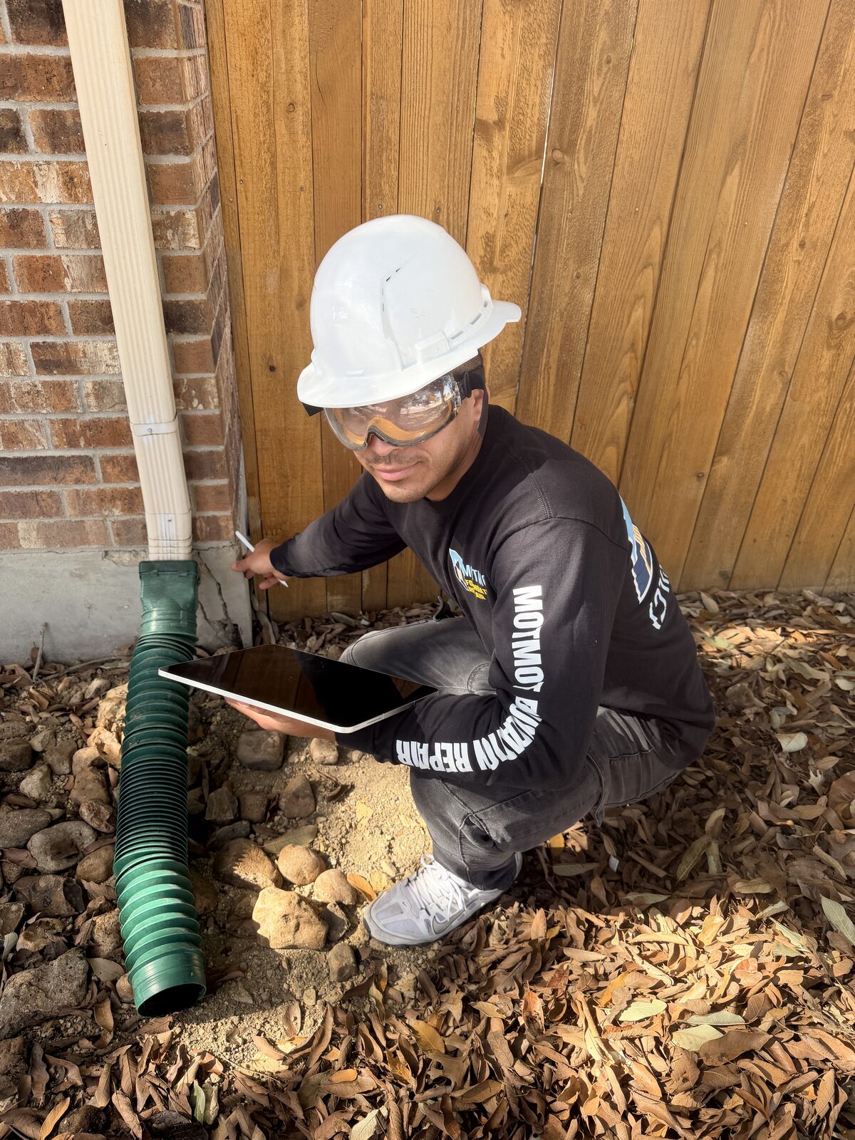 Inspector checking a downspout extension that routes roof runoff away from a home's foundation