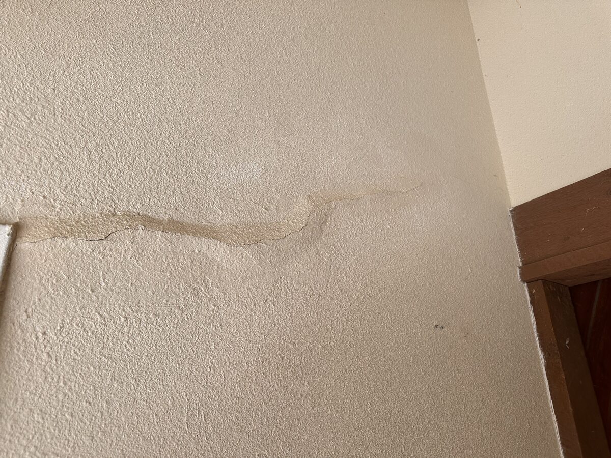 Jagged horizontal plaster crack across an interior wall of an older settling home