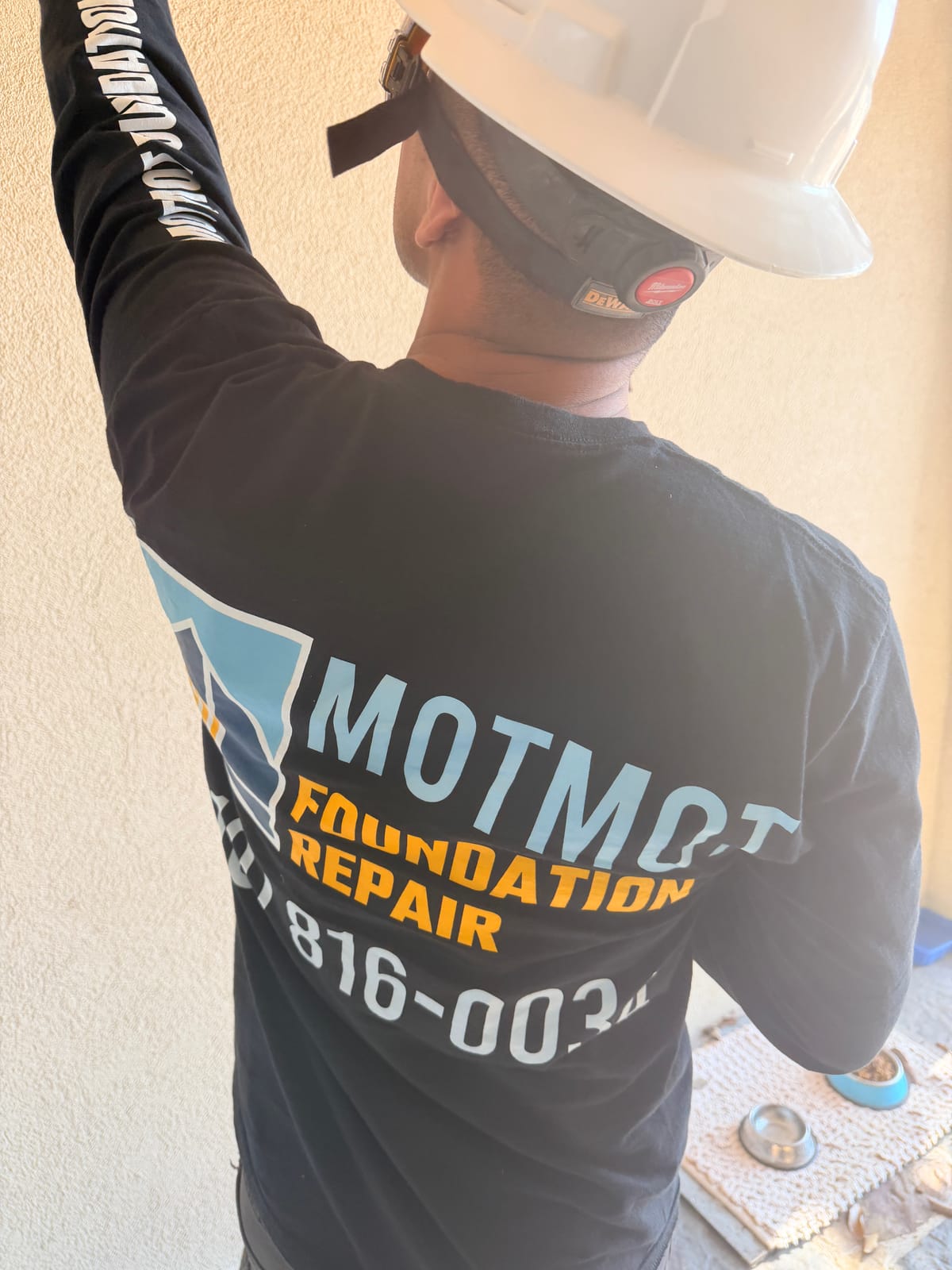 Motmot Foundation Repair crew member documenting foundation cracks on a home exterior during inspection