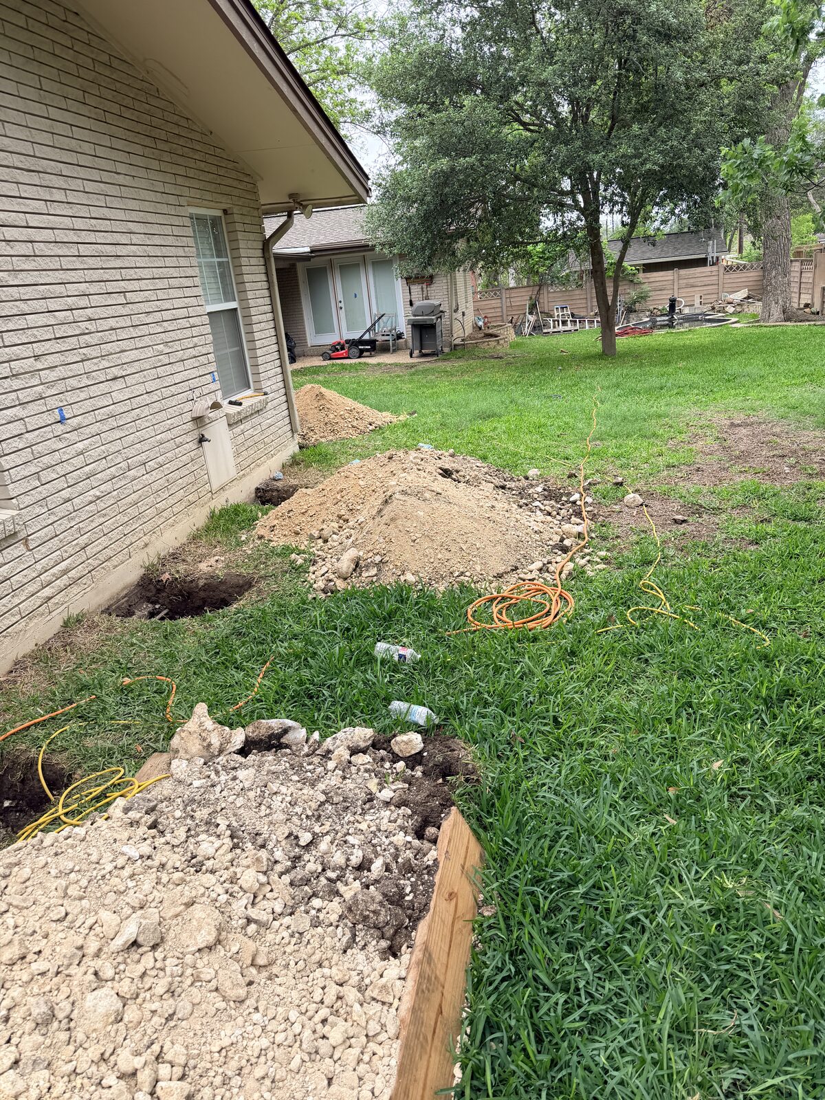 Line of foundation pier excavations wrapping a home's corner, dug to lift and level the slab