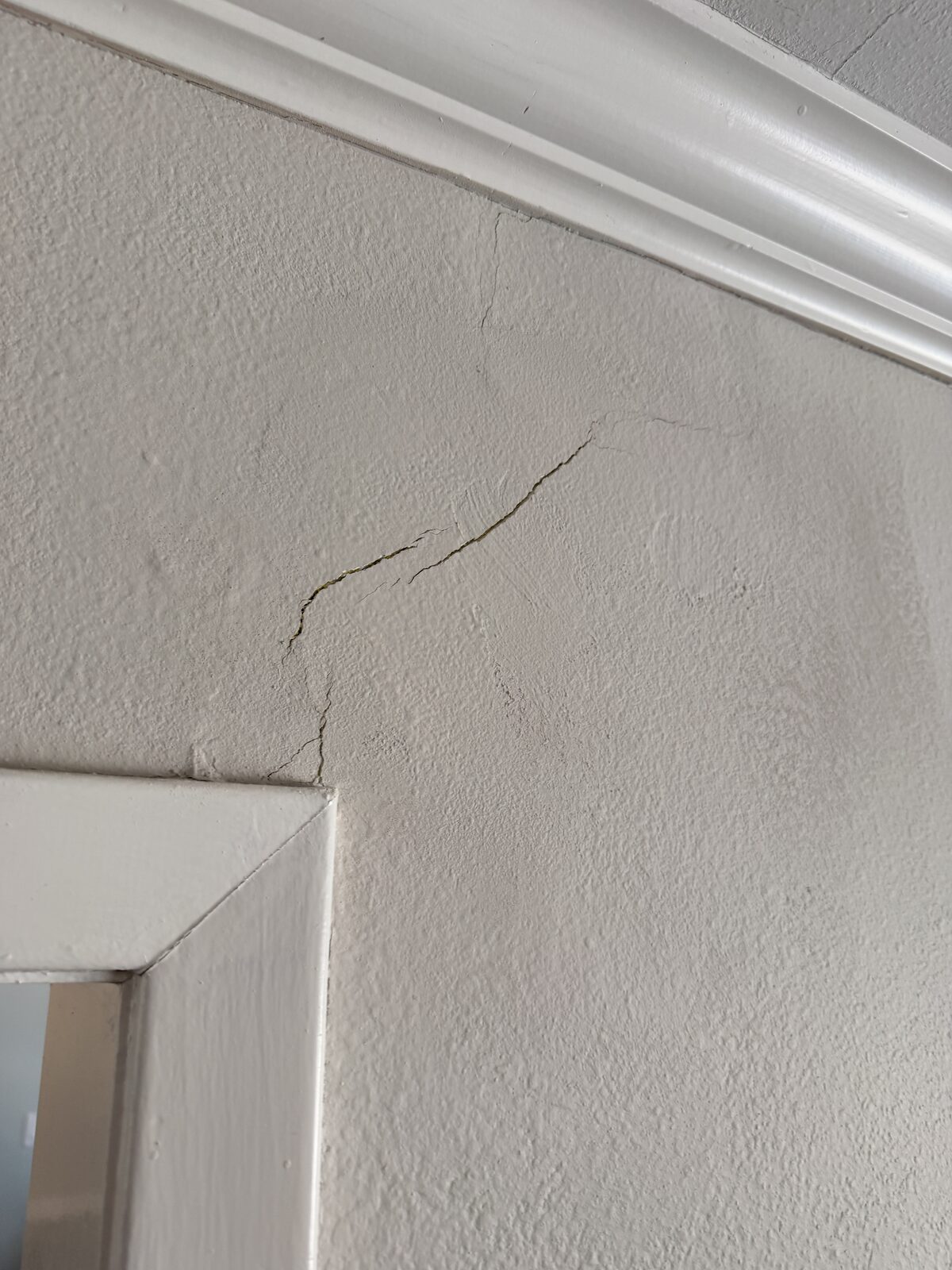 Plaster wall crack near the crown molding, documented during a foundation settlement inspection