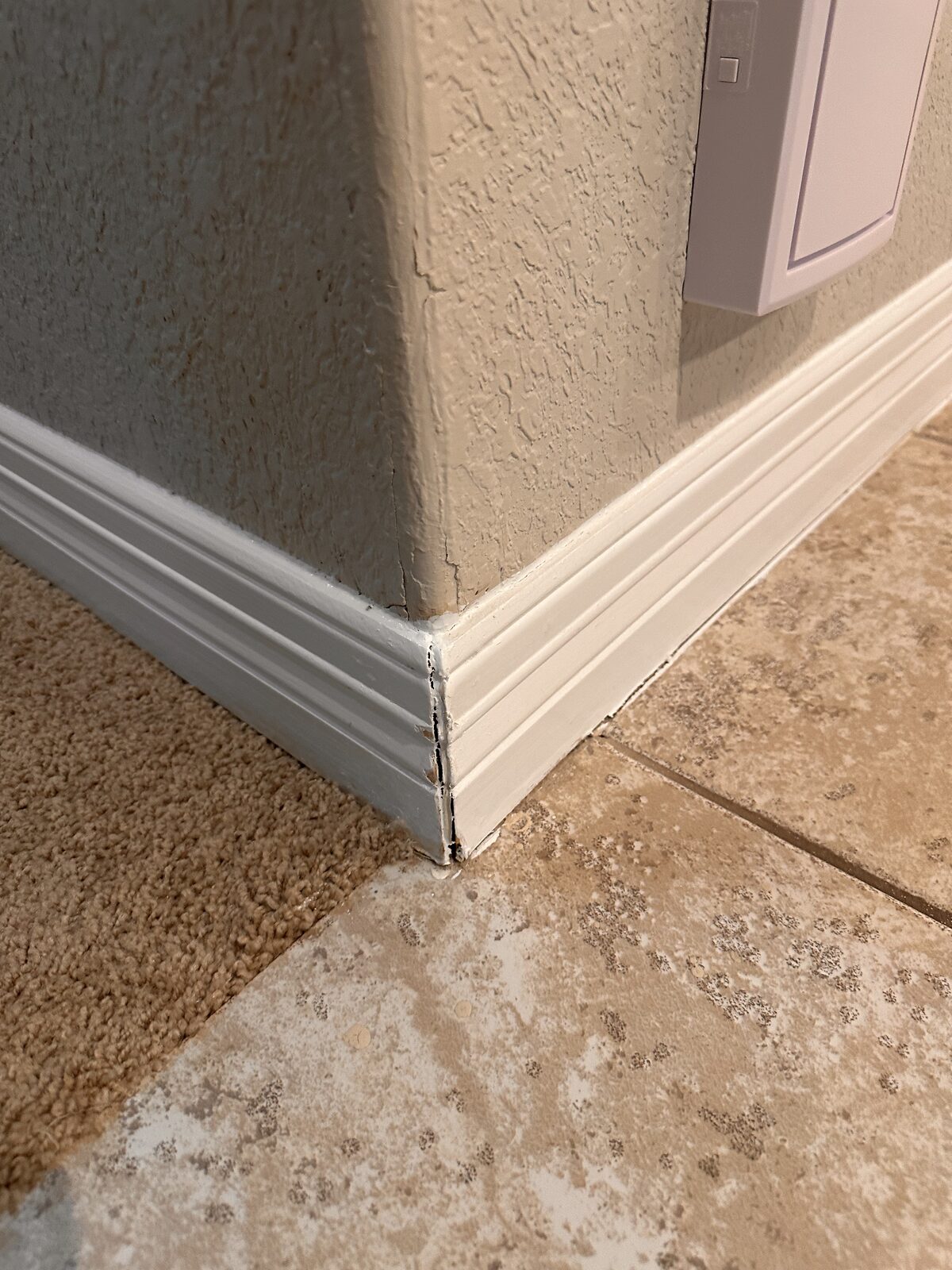 Trim separating at the base of a stucco porch column, an exterior sign of foundation settlement