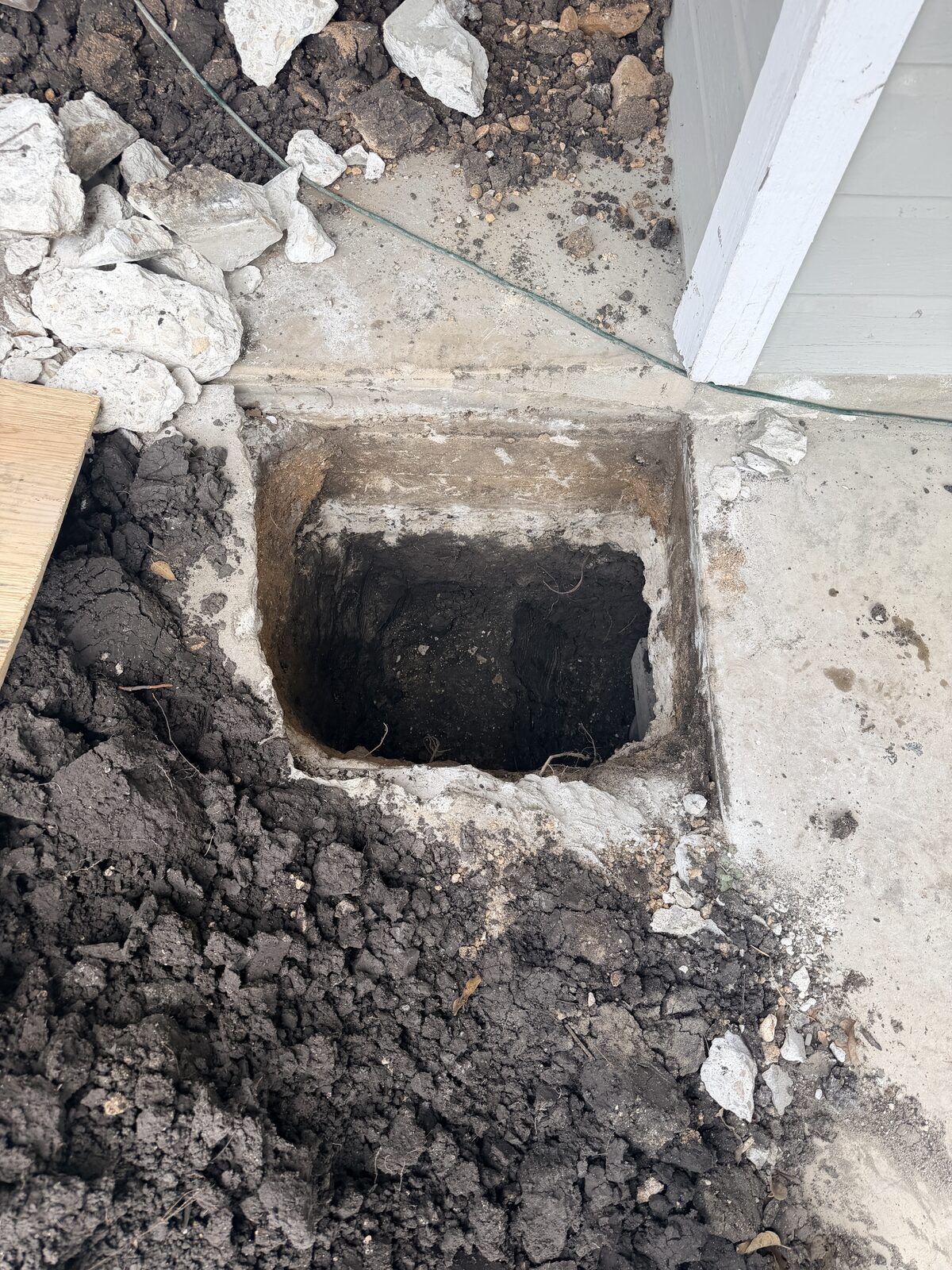 Square pier pit dug at the foundation edge with concrete removed to set a new support pier