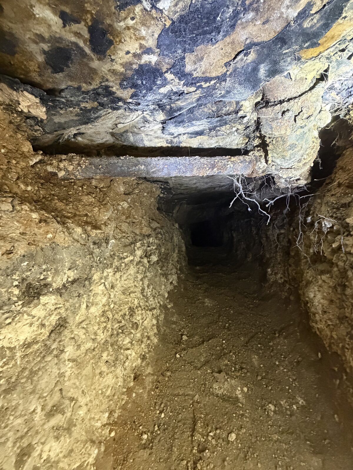 Access tunnel hand-excavated beneath a slab foundation for under-slab plumbing and foundation repair