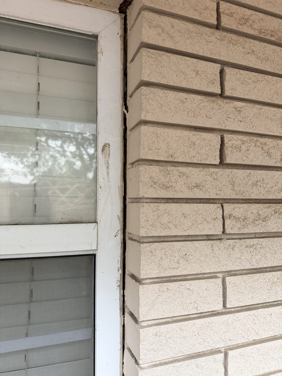 Crack tracing from the soffit down a stone veneer wall to the window header before pier installation