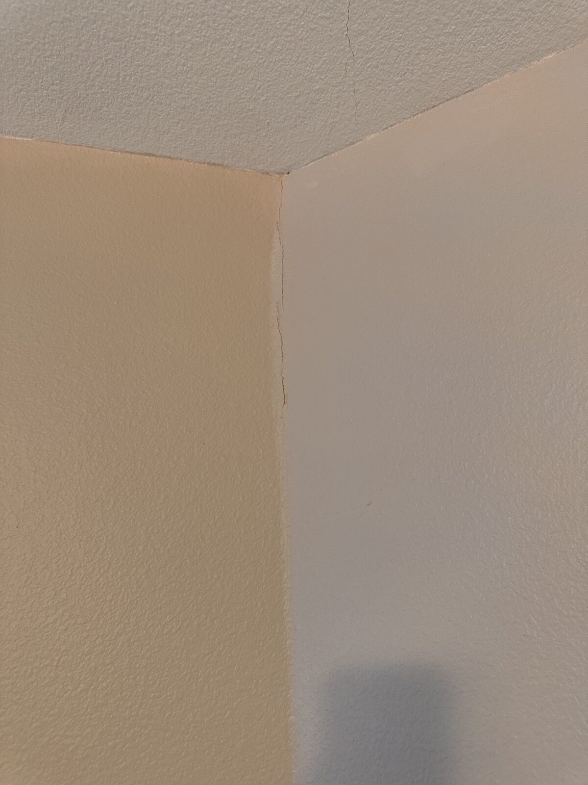 Vertical drywall crack along an interior room corner caused by foundation settlement