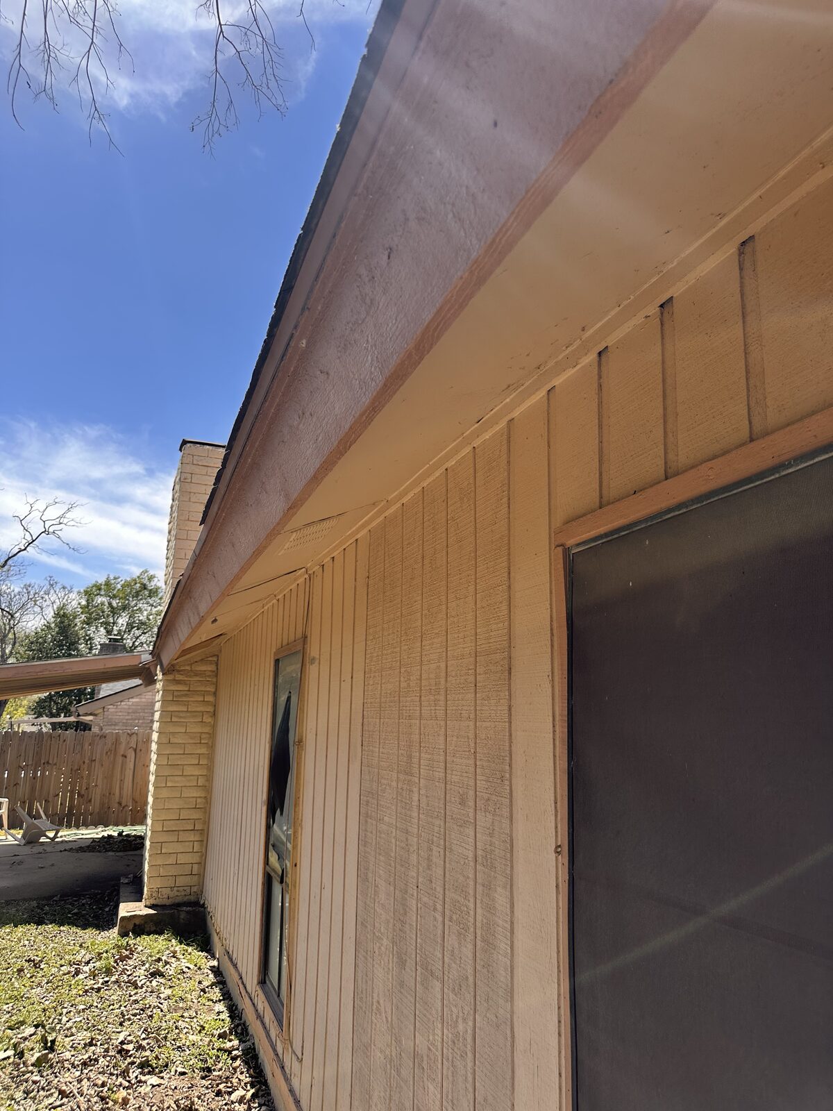 Wood-sided home exterior viewed along the eave line during a structural and foundation assessment